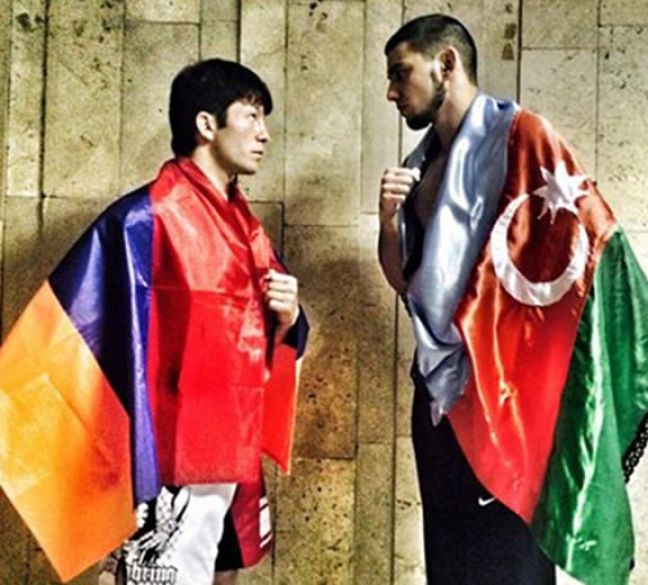 Albert Kazaryan (left) greets his Azerbaijani opponent Ruslan Muratazov clad in the Armenian and Artsakh flags